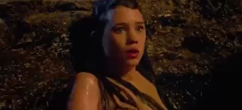 A sexy girl is sitting in the water and showing her boobs.