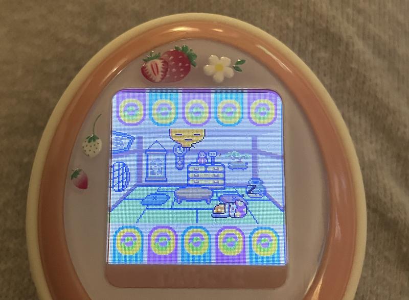 close up photograph of a tamagotchi plus color device. memetchi is bored with being a parent now and floating away