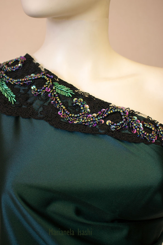 Long evening dress in satin bottle green with asymmetrical one-shoulder design and lace and rhinestone details.
