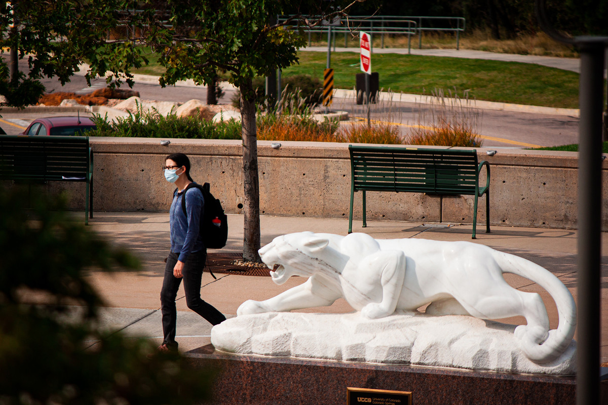 A student walking on campus wearing a mask.