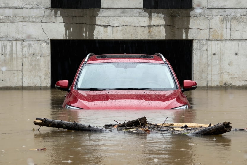 flood-damaged red SUV partially submerged in muddy water