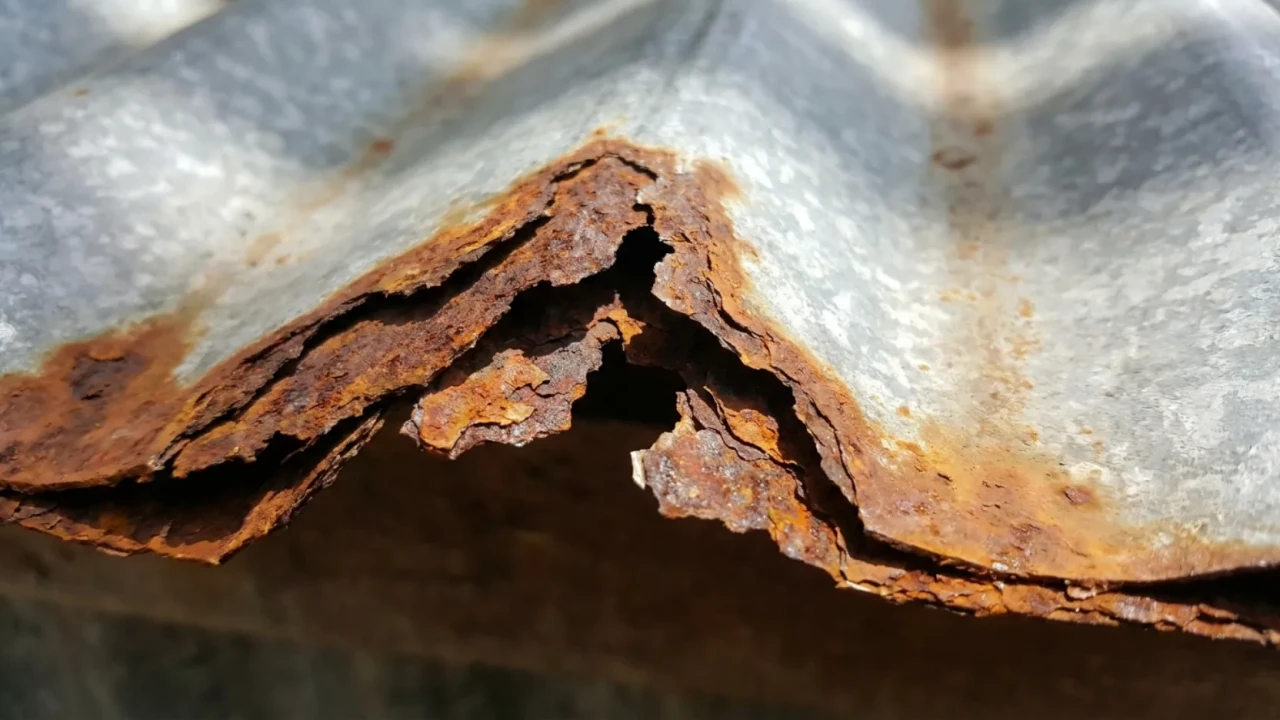 Galvanized steel roof panel showing rust progression at cut edges and surface pitting after years of exposure