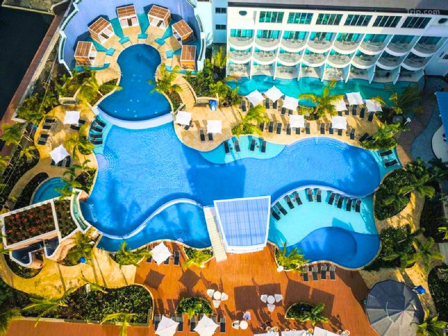 مسبح جميل في Hampton by Hilton Dubai، محاط بكراسي استرخاء وأجواء هادئة مثالية للراحة تحت أشعة الشمس.