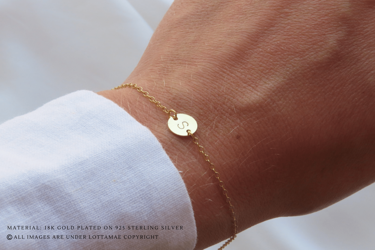 This dainty and personalizable disk bracelet is the perfect way to show off your personality. Crafted from 925 sterling silver and 18k gold plated, this bracelet is sure to turn heads wherever you go. The initial of your choice will be hand stamped onto the disk, making it a totally unique piece of jewelry that you can wear with pride. Whether you choose your own initial or a special memento of someone close to you, this bracelet is a wonderful way to express who you are. Perfect for everyday wear, it will add a touch of elegance to any outfit. Add this beautiful and personalized piece of jewelry to your collection today!