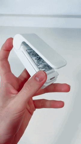 Hand holding the mini sealer and pressing it along a food bag
