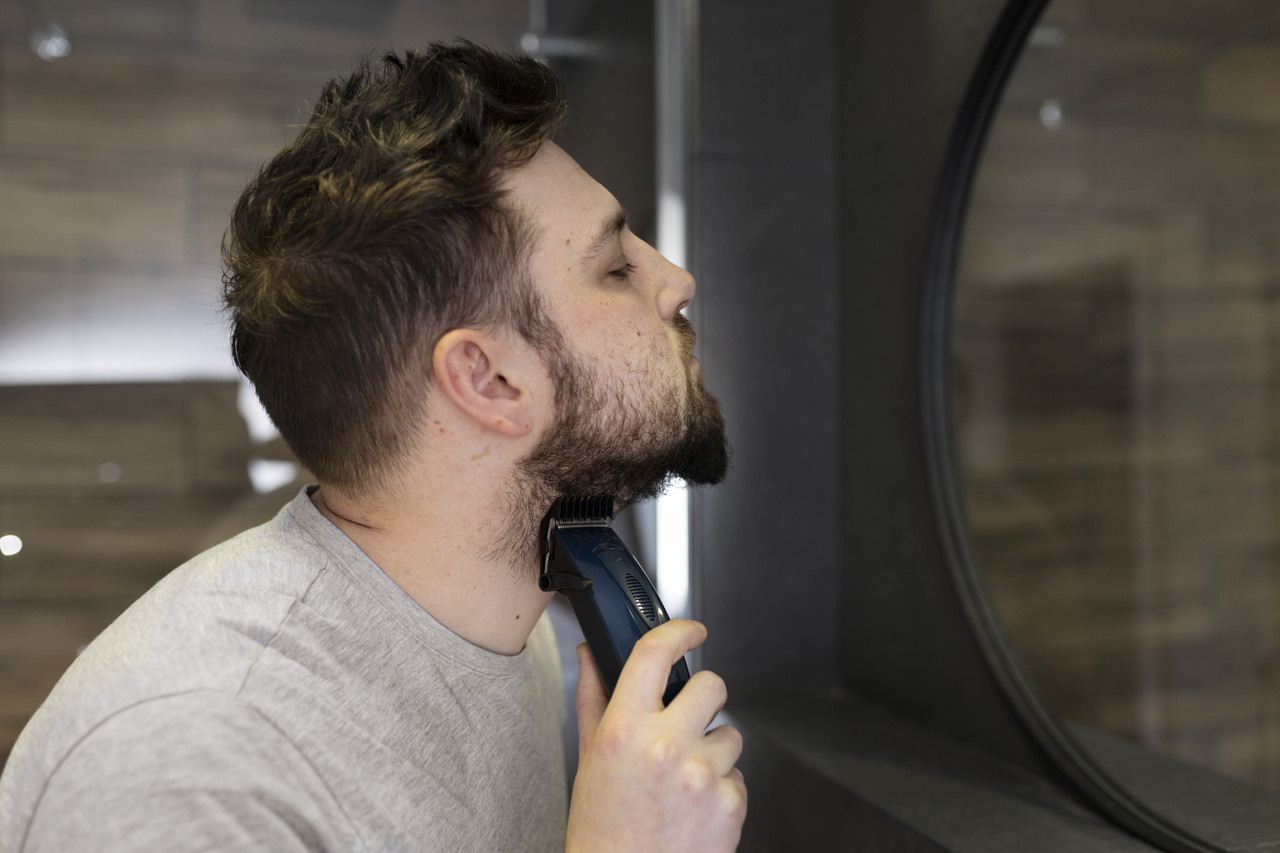 young man trimming his beard mirror