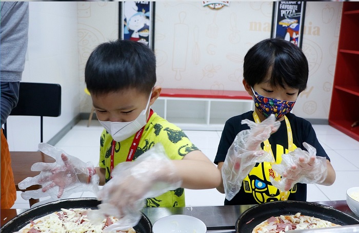 Pengunjung KidZania Surabaya mencoba profesi sebagai juru maska pizza.