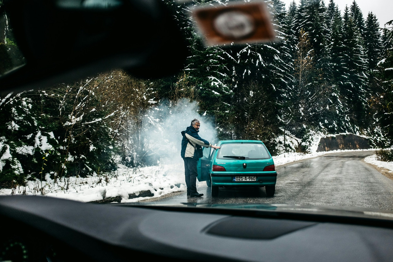 Man standing in the road with broken car