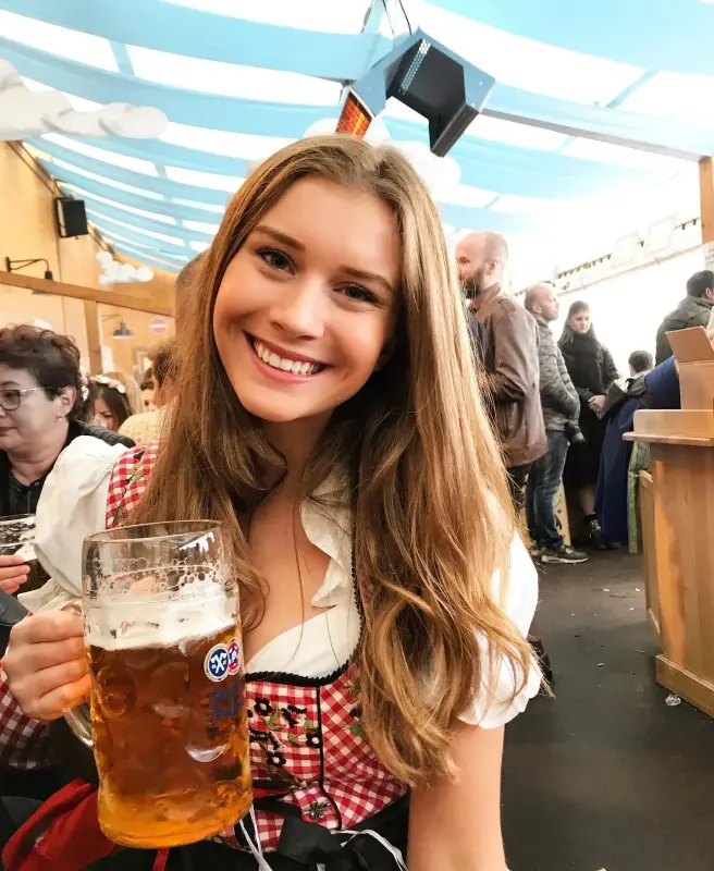 Chica alemana con una amplia sonrisa sosteniendo una enorme jarra de cerveza