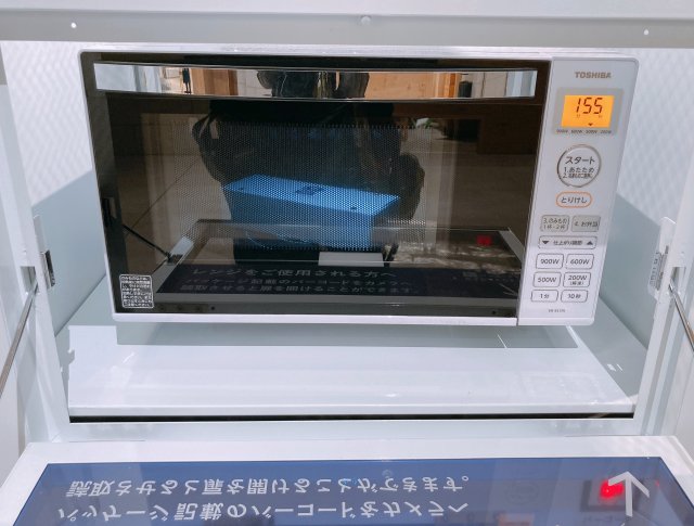 Microwave di samping mesin penjual otomatis yang disediakan untuk menghangatkan oyster goreng.