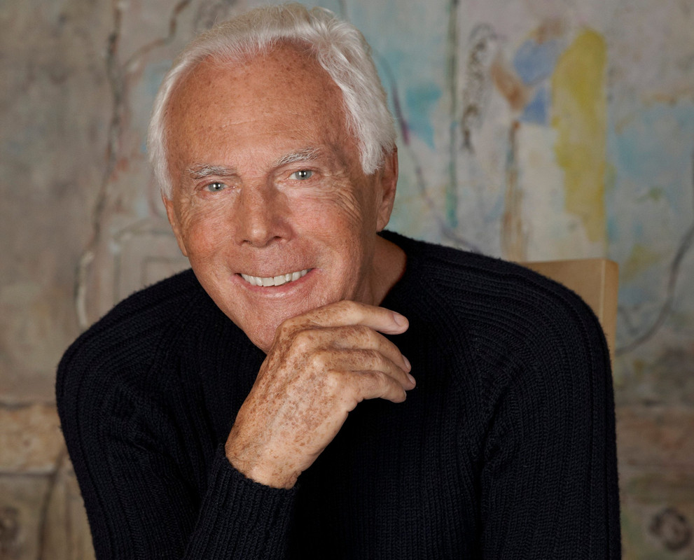 Un ritratto senza tempo di Giorgio Armani, nato l'11 luglio 1934, mentre celebra il suo compleanno. Il Maestro dello stile italiano, la cui visione ha ridefinito il lusso contemporaneo, continua a ispirare il mondo della moda. Primo piano di Giorgio Armani nato l'11 luglio 1934 che sorride mentre poggia la mano sul mento, con uno sfondo sfocato di colori pastello.