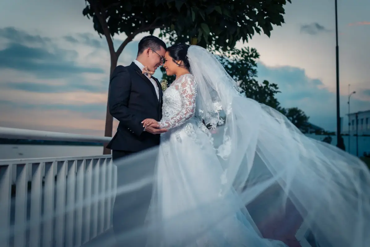 Pareja de recién casados mirándose con velo al viento
