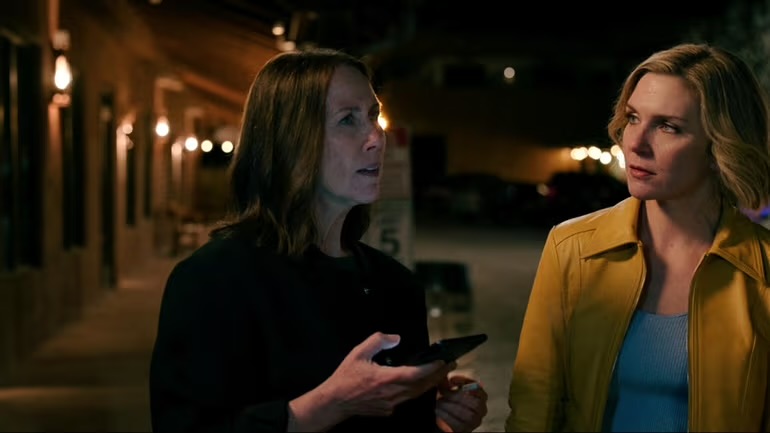 still frame from pluribus showing Carol and her girlfriend standing outside together on the night individualistic human society ended