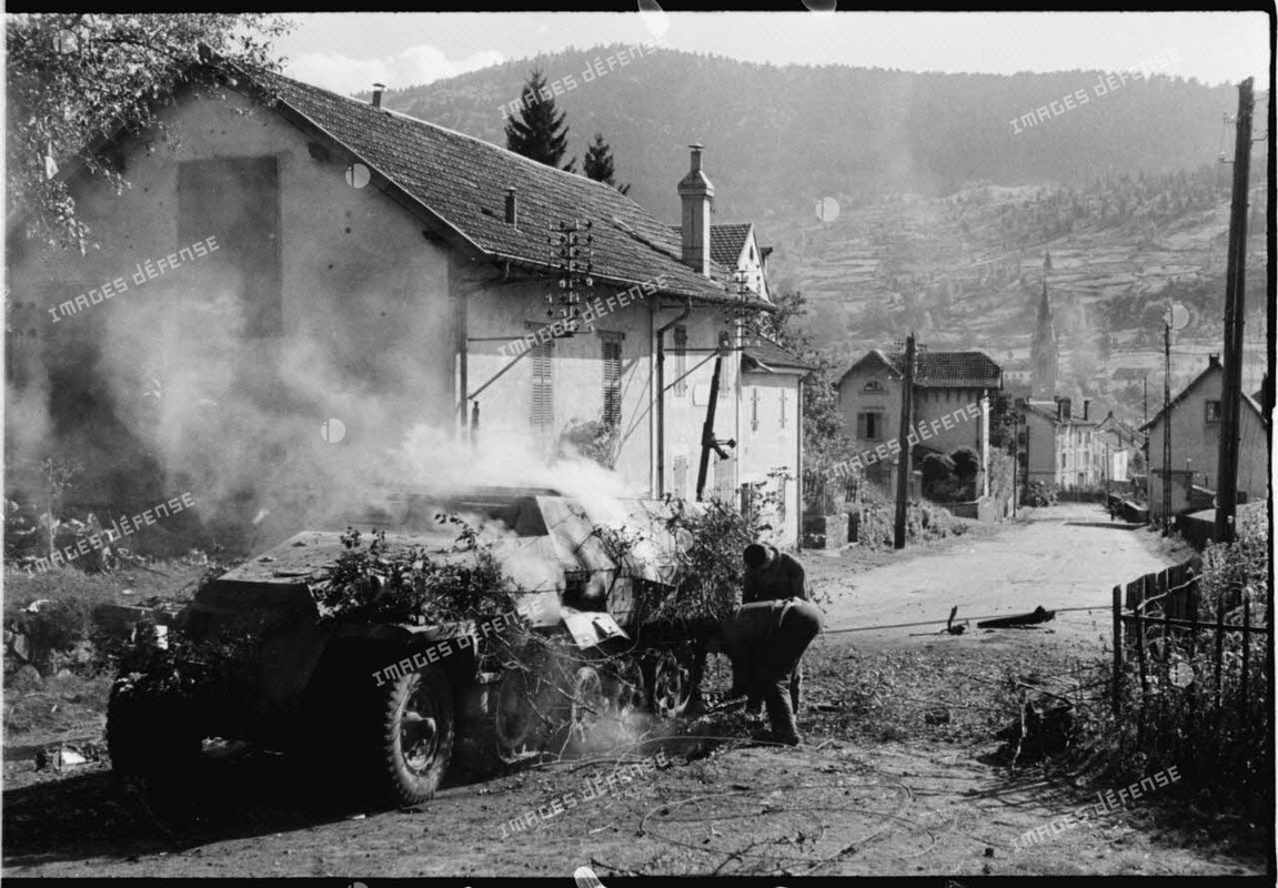 Une automitrailleuse semi-chenillée allemande Sd.Kfz 251 vient de sauter sur une mine dans le villag