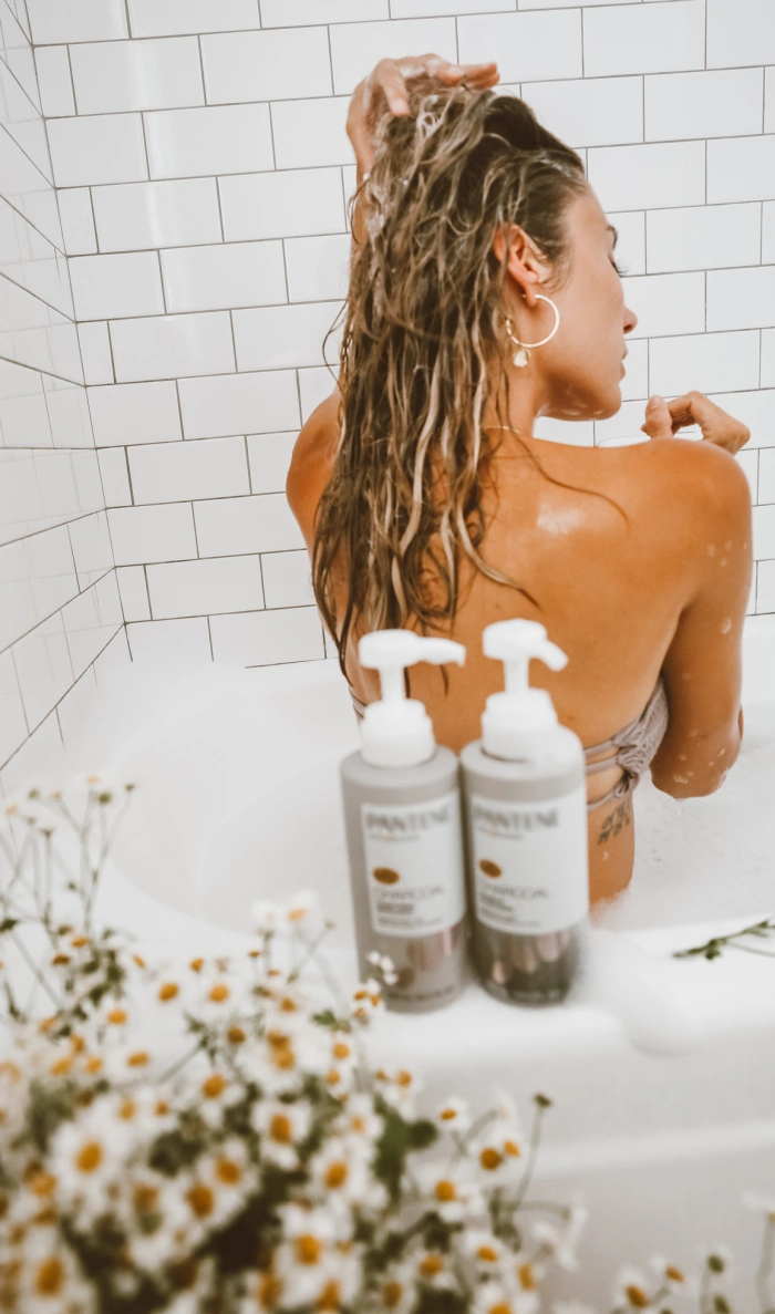 A woman washes her hair in a bathtub