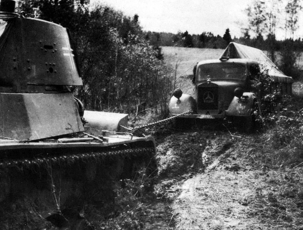 Трофейный советский танк Т-26 вытаскивает из грязи немецкий грузовик Mercedes-Benz L 3000.
