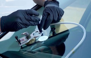Technician performing windshield chip repair on a vehicle