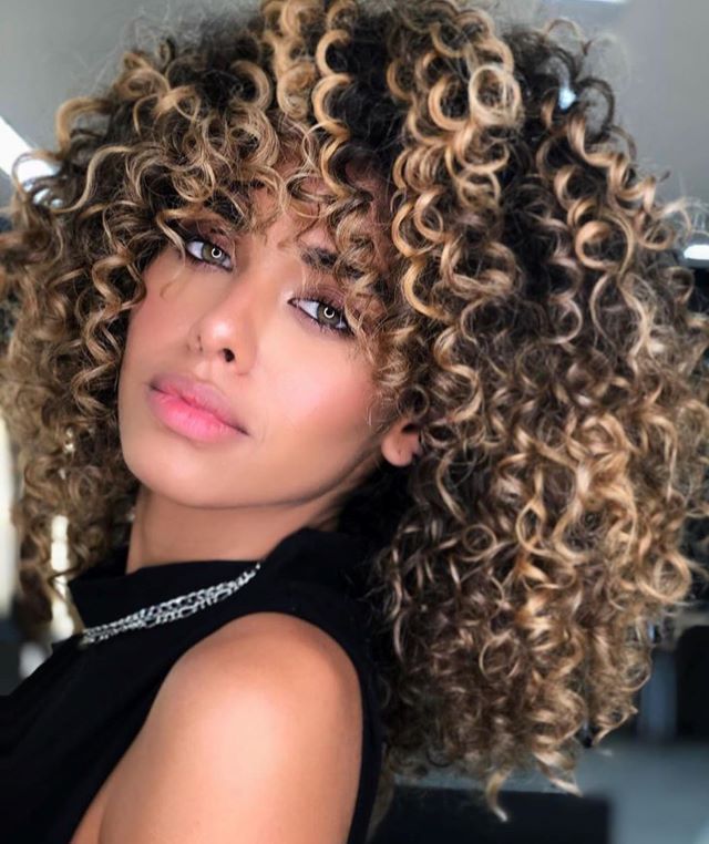 Devojka sa kovrdžavom kosom sa pramenovima boje meda