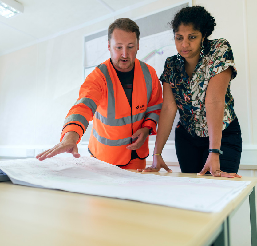 engineer with outstretched hand explaining engineering plans to woman owner