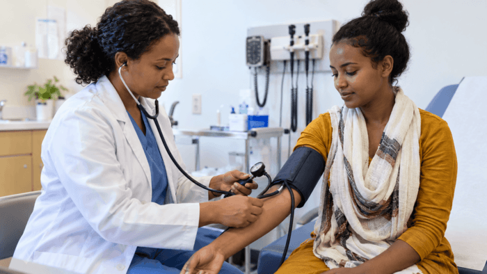 Ethiopian female doctor checking a domestic worker candidate's blood pressure during a medical fitness assessment for overseas employment.