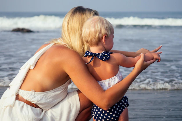 beautiful-fair-haired-mother-hug-daughter-sea-beach-happy-family-vacation-travel-mom-show-her-child.webp