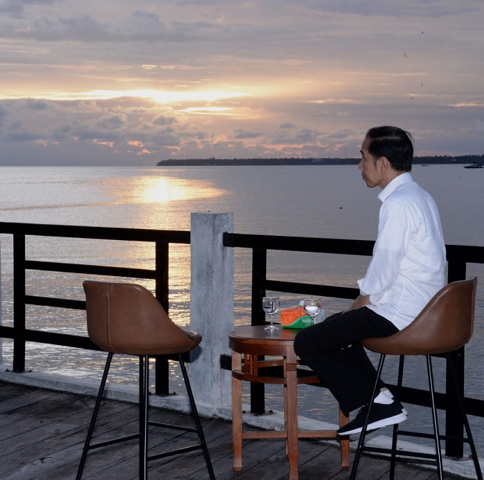 Jokowi duduk di satu kursi dan menghadap pemandangan Laut Arafuru.