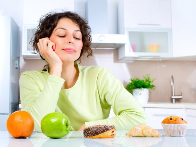 devojka gleda u voće i slatkiše