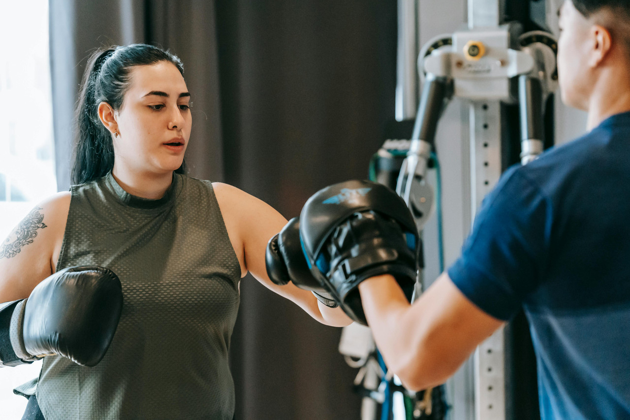 Adult doing a conditioning workout in a gym with a personal trainer as part of a realistic fat loss plan