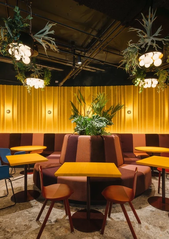 Warm restaurant lighting with illuminated tables, plants and wall surfaces at Le big TamTam
