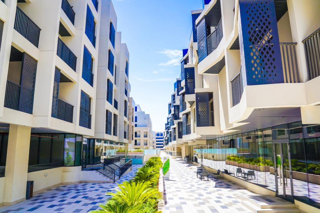 Exterior architectural view of Nasayem Avenue - Block 2 residential building in Mirdif Dubai featuring modern mid-rise apartment design, landscaped surroundings and residential lifestyle setting, highlighted as a Distress Deal investment opportunity