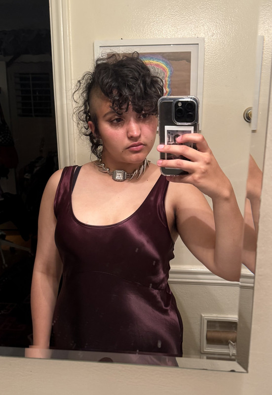 mirror selfie of myself in a burgundy slip dress, a silver choker with a watch piece in the center, silver earrings, and a styled mohawk