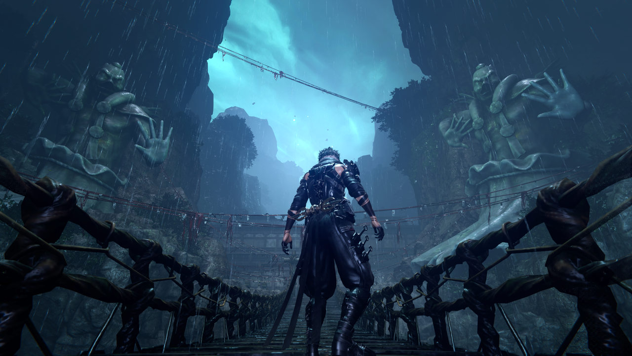 Yakamo stands on a bridge facing two giant statues of daemons on the side of a mountain.