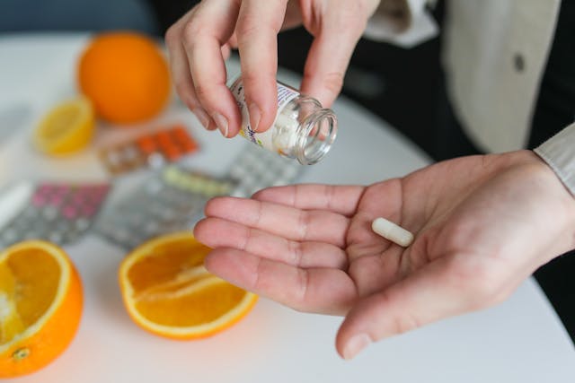 Vitamin C supplements and an orange showing vitamin C as an essential nutrient for healthy skin from external sources.