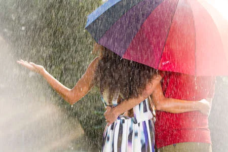 74818958-man-and-woman-under-rainbow-umbrella-in-the-summer-rain.webp