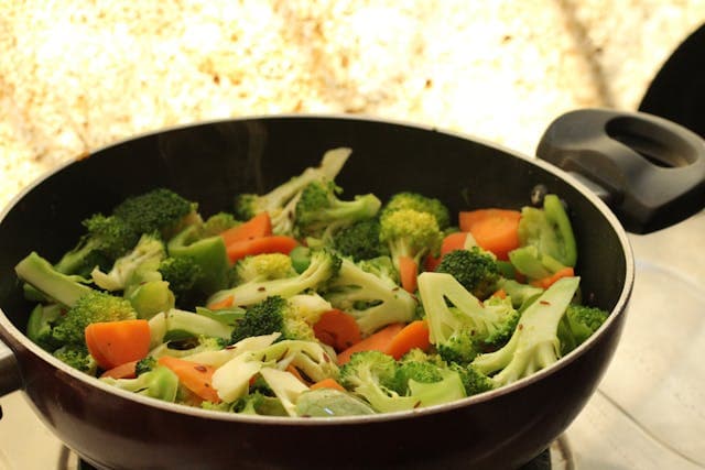 A pot containing broccoli on a stove