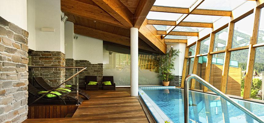 Bright sunlit indoor pool room with glass roof