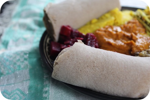 Elegant Ethiopian vegan catering spread with colorful stews and injera bread on a decorated table