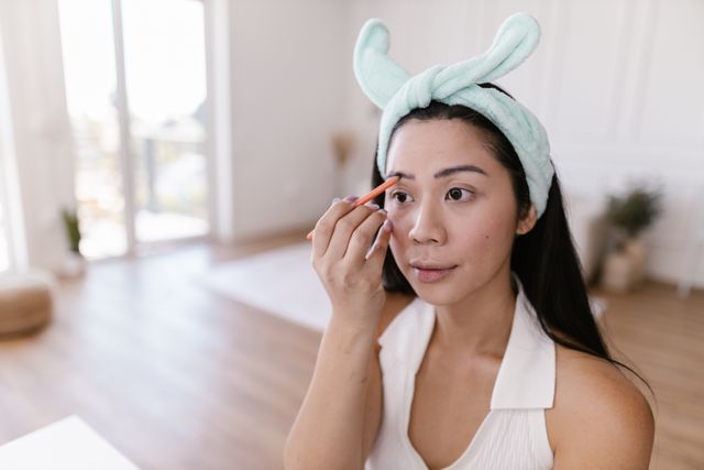 a woman filling her eyebrows with an eyebrow pencil 