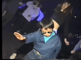 A gif of a young boy in sunglasses dancing at a disco with his arms splayed out.