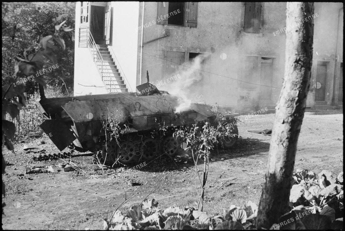 Une automitrailleuse semi-chenillée allemande Sd.Kfz 251 vient de sauter sur une mine dans le villag