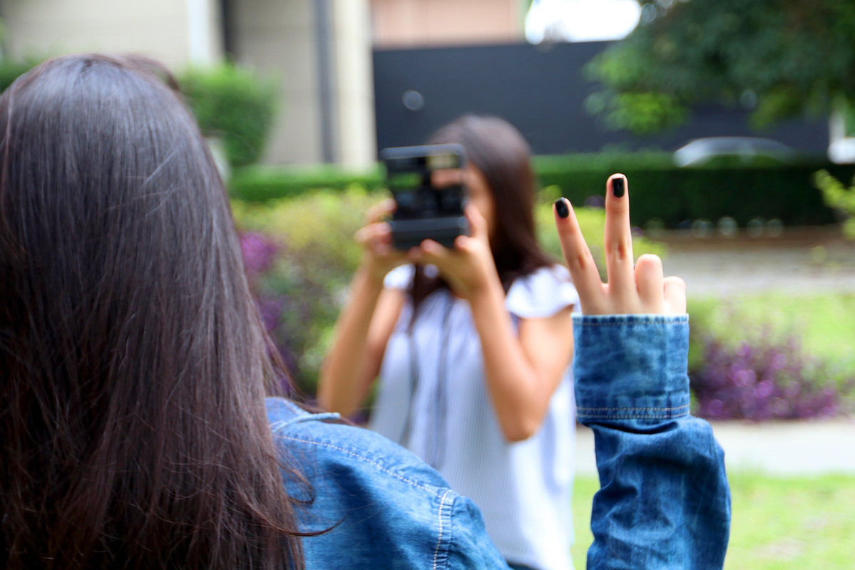 Seorang perempuan tengah berfoto dengan pose peace di depan kamera