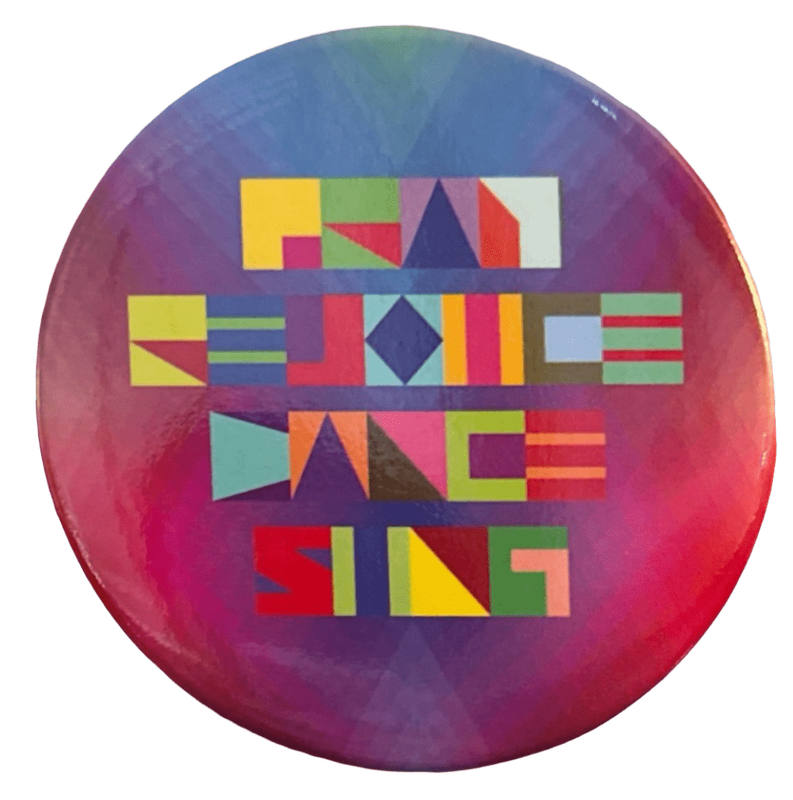 a pin of a piece of jeffrey gibson's art from his exhibit at the broad. it features bright colors, the background mostly red blue and purple, and a stylized font with the text 'PRAY REJOICE DANCE SING'