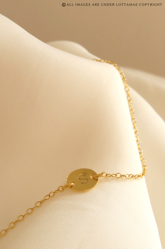 This dainty and personalizable disk bracelet is the perfect way to show off your personality. Crafted from 925 sterling silver and 18k gold plated, this bracelet is sure to turn heads wherever you go. The initial of your choice will be hand stamped onto the disk, making it a totally unique piece of jewelry that you can wear with pride. Whether you choose your own initial or a special memento of someone close to you, this bracelet is a wonderful way to express who you are. Perfect for everyday wear, it will add a touch of elegance to any outfit. Add this beautiful and personalized piece of jewelry to your collection today!