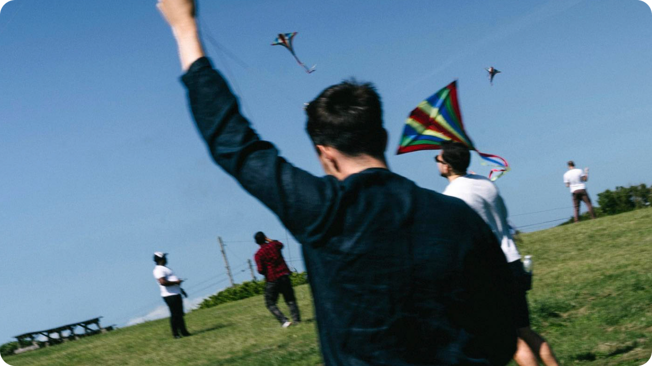 Five people flying kites in an open field.