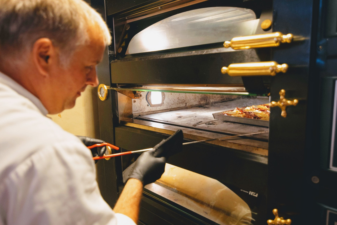 Chef placing pizza into oven during restaurant environmental photography