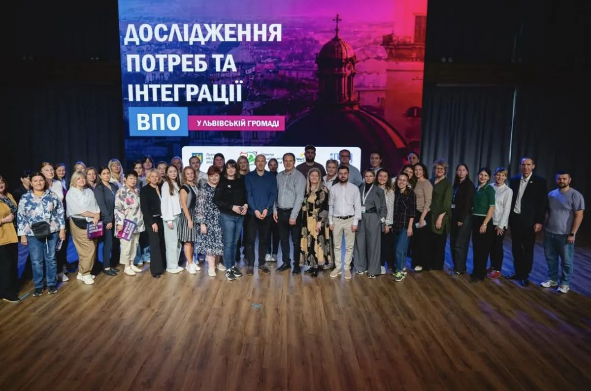 Груповий знімок учасників на тлі екрана з назвою дослідження потреб та інтеграції ВПО у Львівській громаді