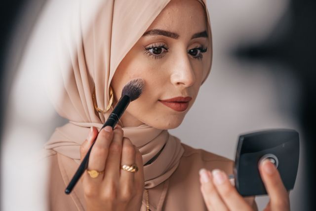 a woman applying makeup on her face and wondering Why does my makeup look patchy  