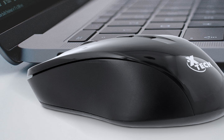 Mouse inalámbrico Xtech junto a una laptop, mostrando un espacio de trabajo limpio.