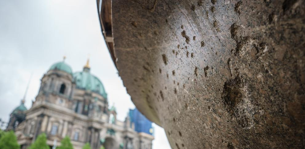 Daños de mortero en el tazón de granito gigante en la plaza Lustgarten, con la Catedral de Berlín al fondo