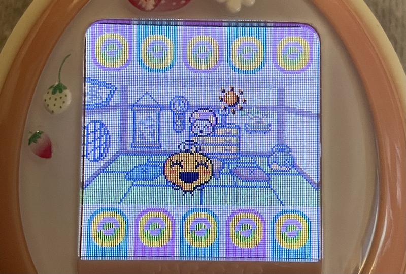 close up photograph of a tamagotchi plus color device. Memetchi is playing with her baby daughter